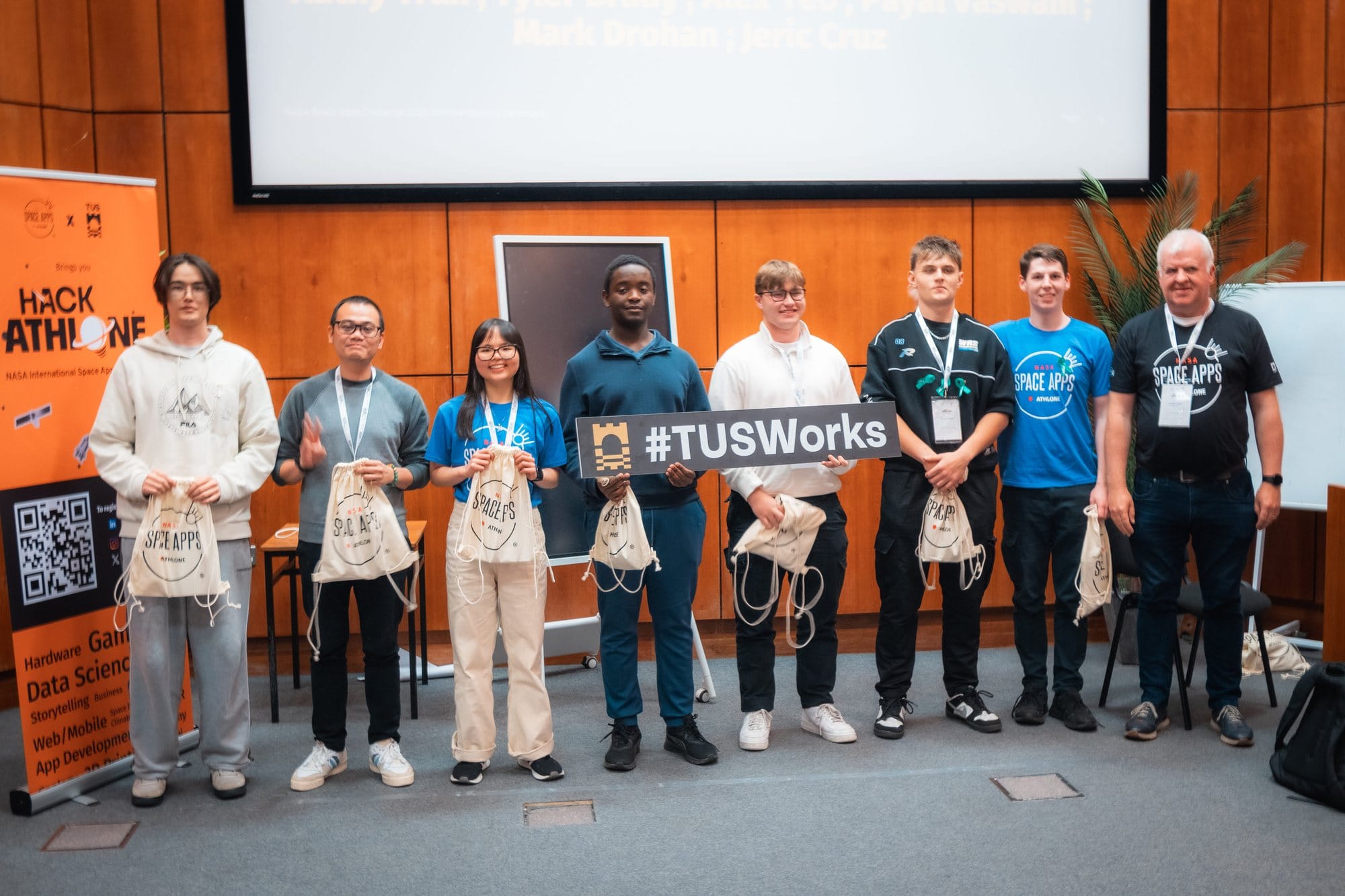 Participants on stage at HackAthlone 2025 with Space Apps bags and a #TUSWorks sign