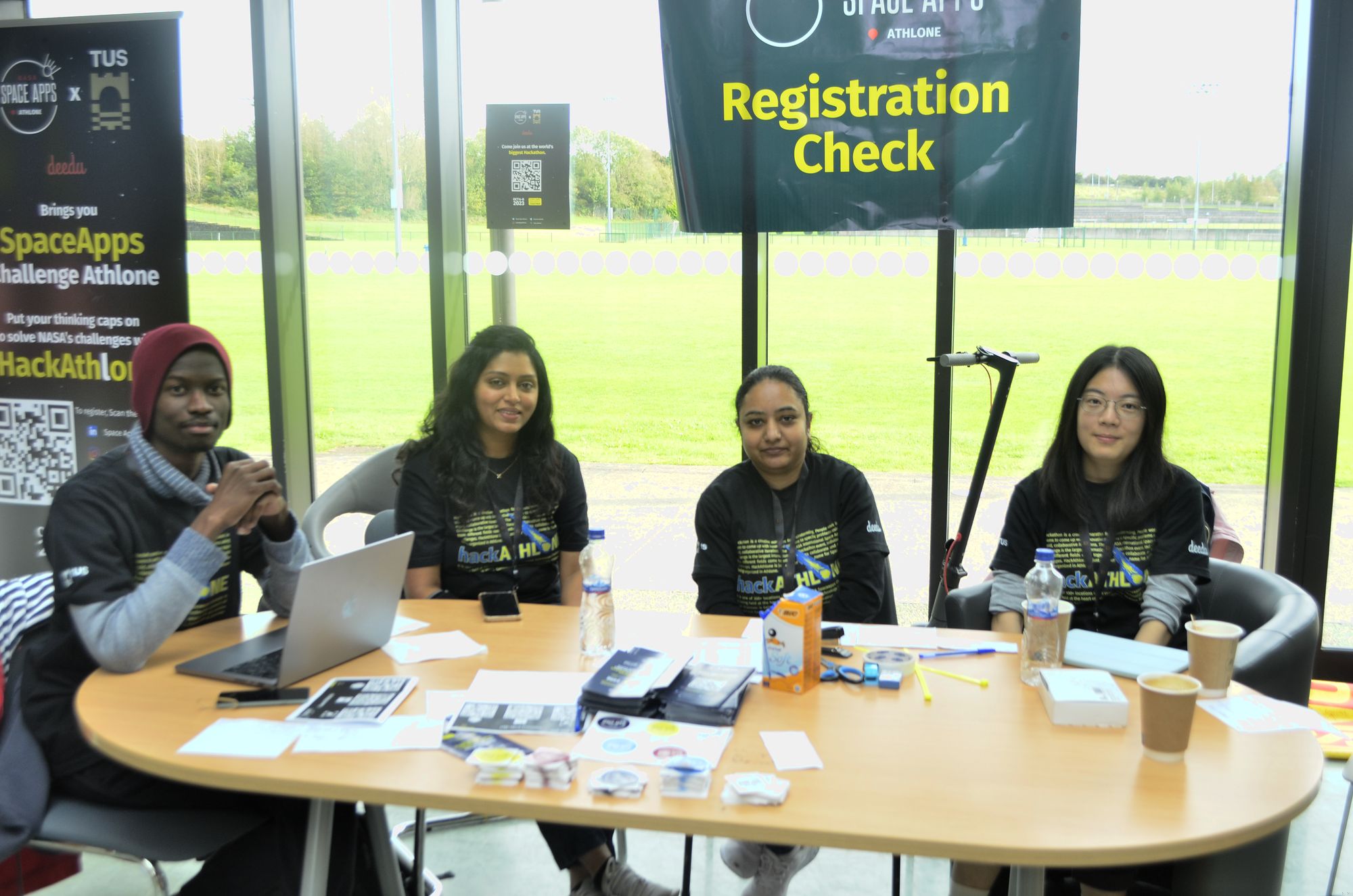 Four volunteers in HackAthlone T-shirts at the Registration Check desk at HackAthlone 2023